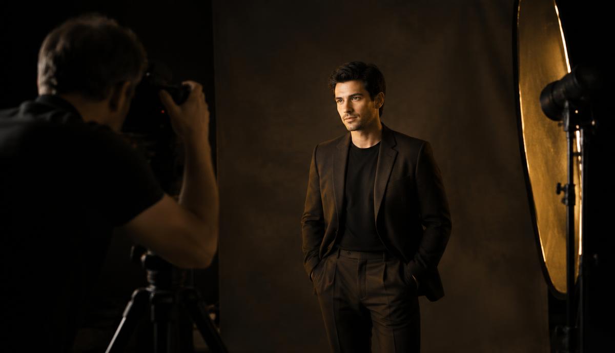 Professional actor headshot photoshoot in a dark studio with photographer and golden studio lighting